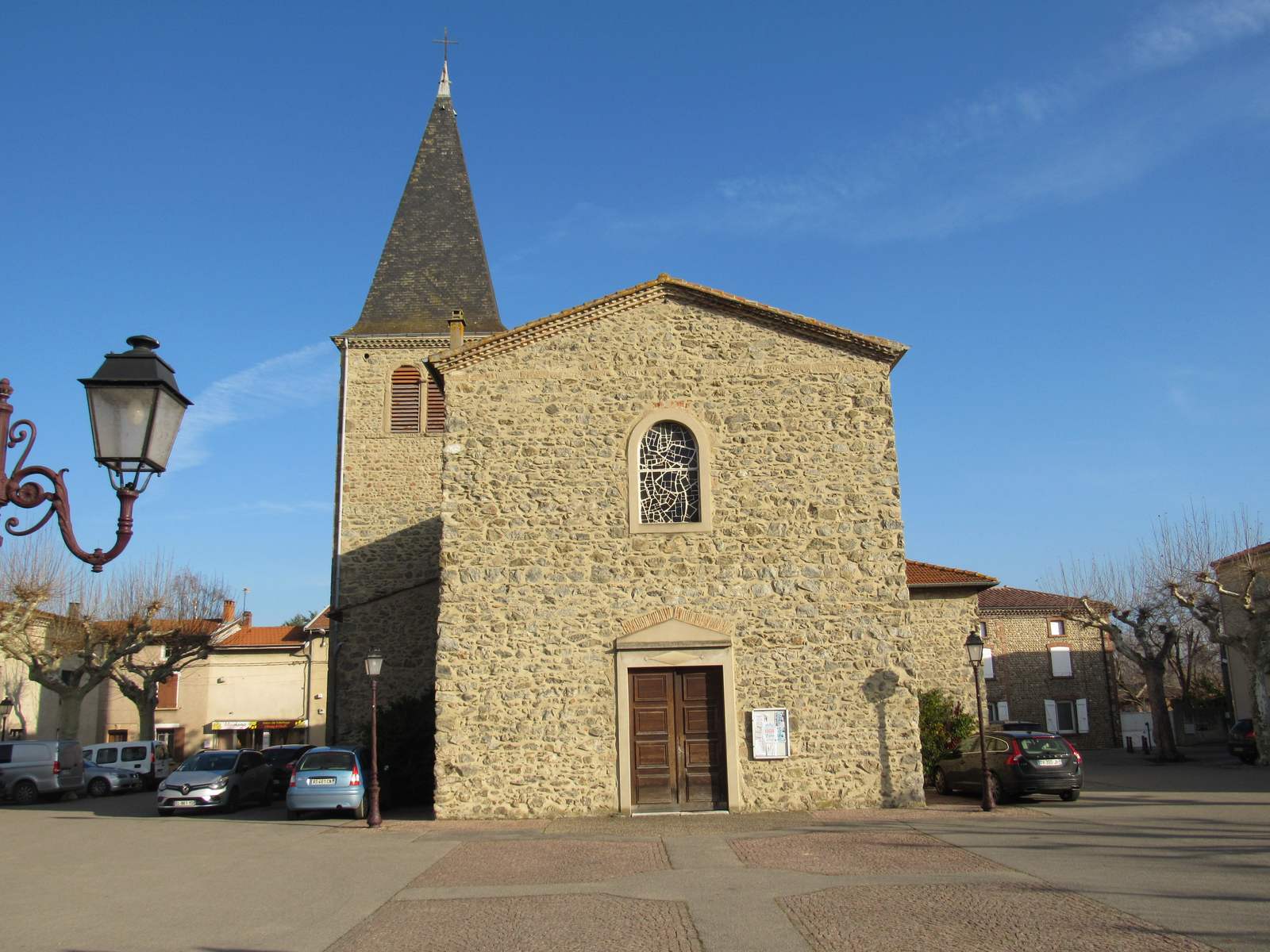La façade en galets de l'église Saint-André d'Andancette et son clocher à flèche d'ardoise, sur la place