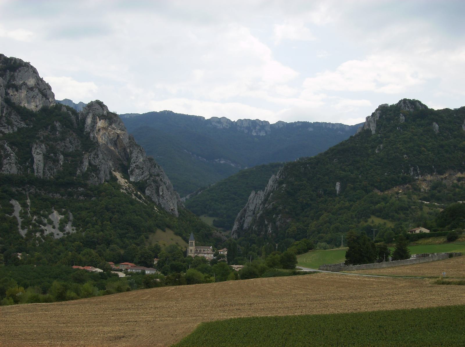 Beauregard-Baret vu depuis la route D125, des champs au premier plan et les falaises calcaires du Vercors en arrière-plan