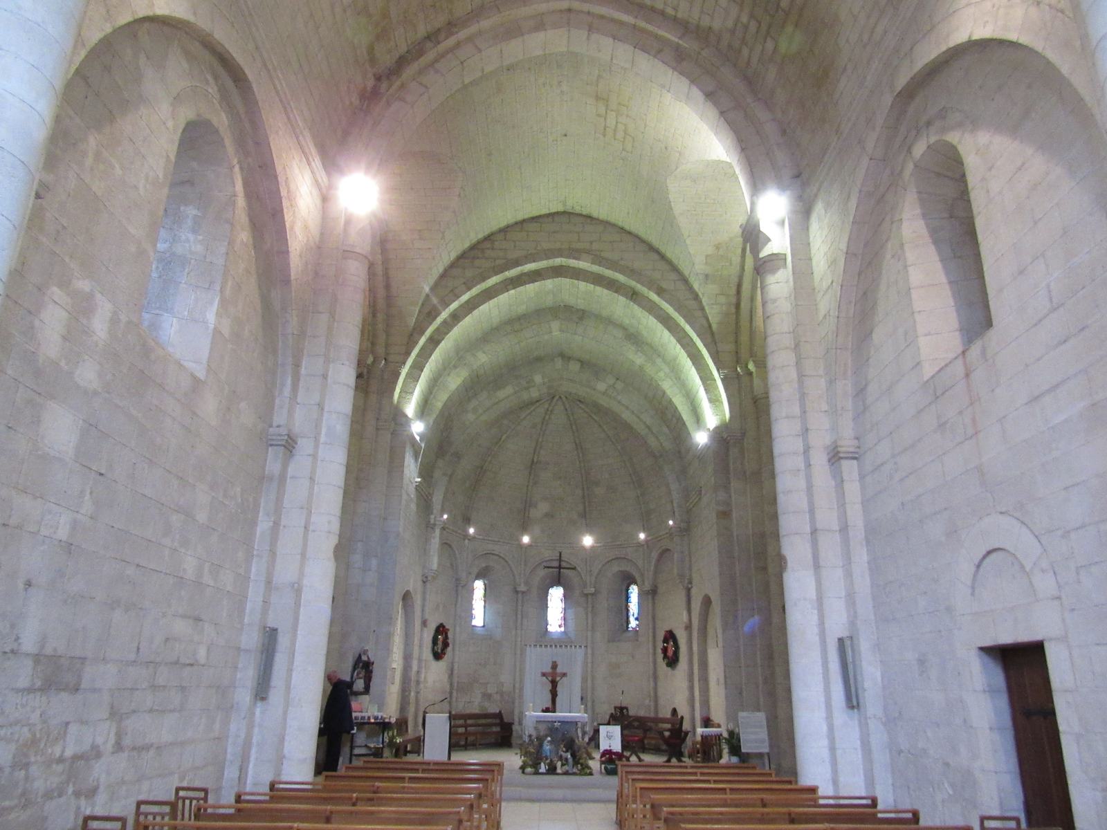 La nef de la basilique Sainte-Anne, voûtée en berceau brisé, aux murs de pierre blanche, avec ses bancs et le chœur éclairé au fond