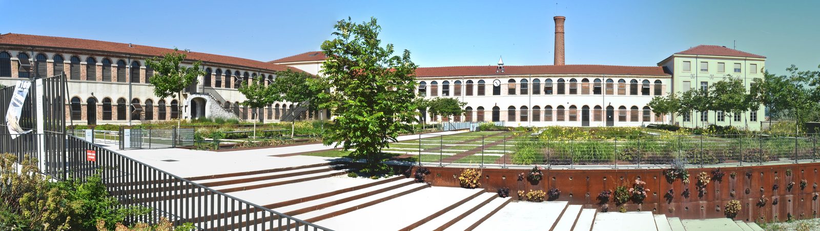 Vue panoramique de la Cartoucherie restaurée, ses bâtiments à arcades et sa cheminée d'usine