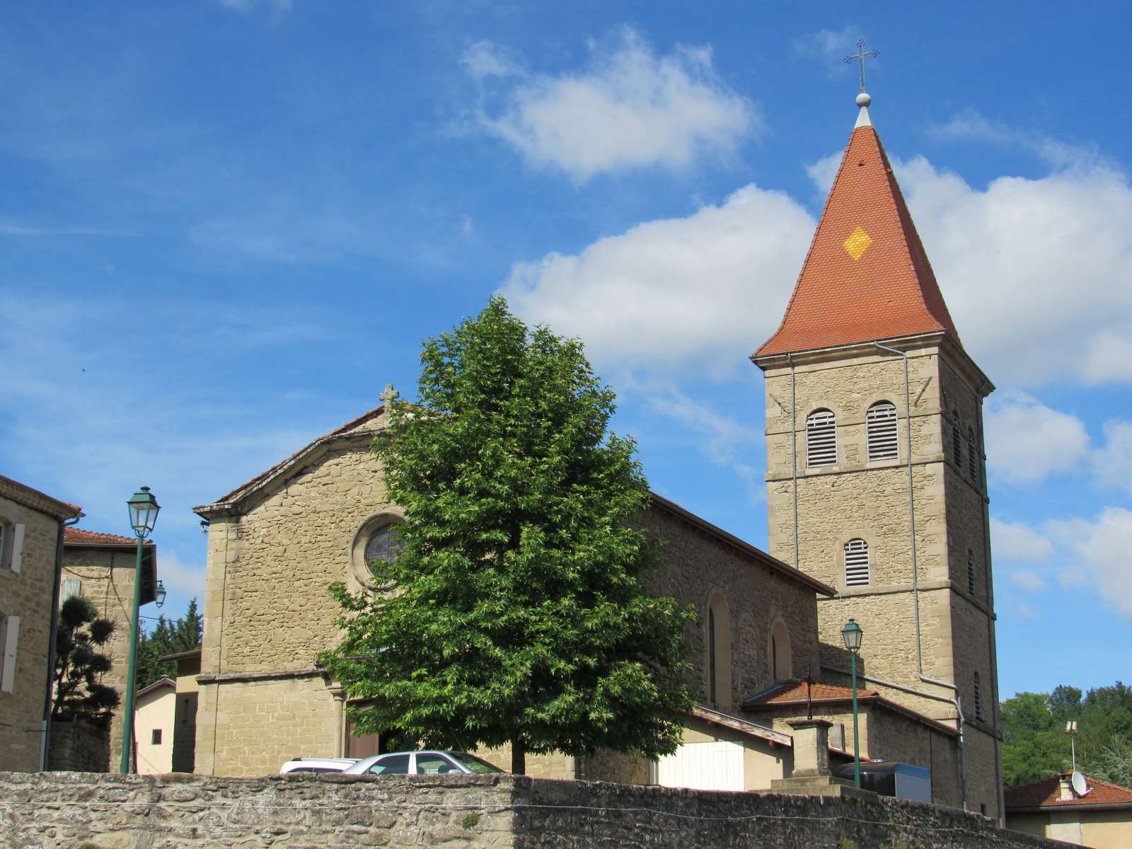 L'église Saint-Sébastien de Claveyson, façade de pierre et haut clocher carré à toit pointu orné d'un losange