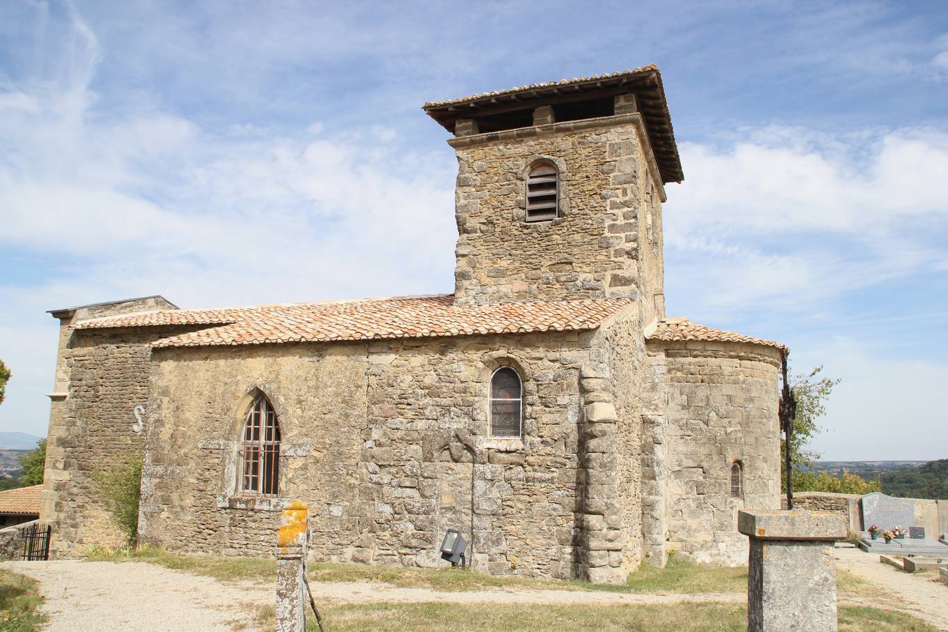 Le prieuré de Saint-Andéol, petite église romane en pierre avec un clocher carré et une abside, dans une cour herbeuse