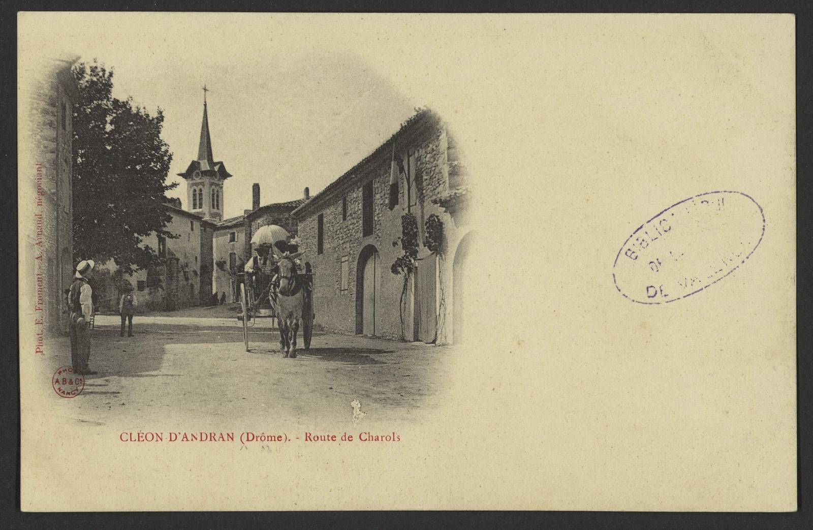 Carte postale ancienne de Cléon-d'Andran, une rue de terre avec une carriole tirée par un mulet, une femme sous une ombrelle, et le clocher pointu au fond