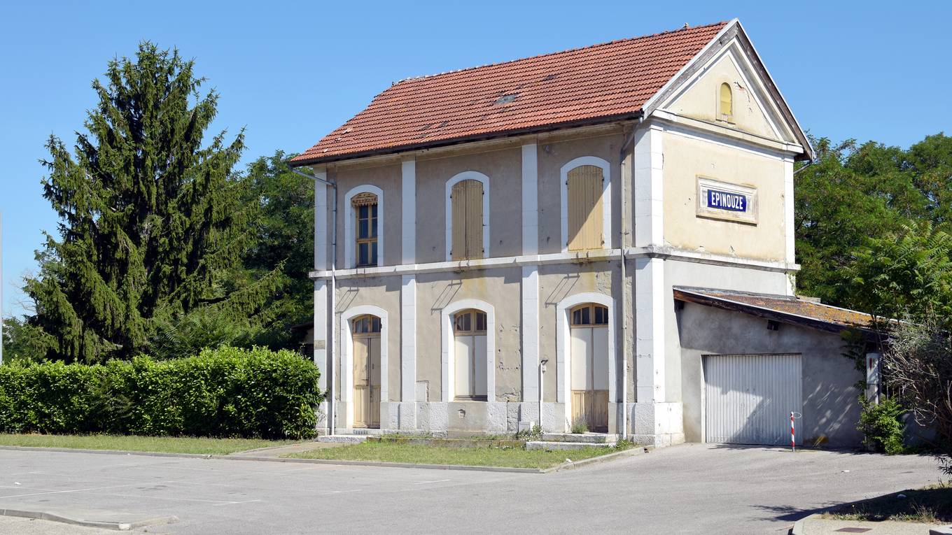 L'ancien bâtiment de gare d'Épinouze, deux niveaux, toit de tuiles et plaque émaillée au nom du village