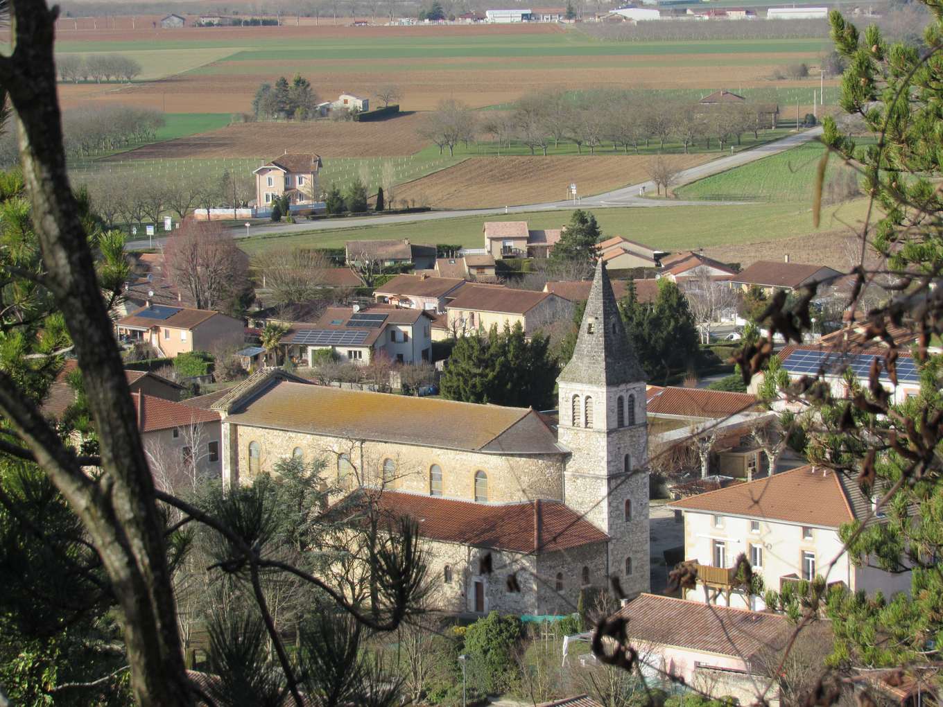 Le village d'Hostun dans la plaine, vu d'en haut, avec l'église Saint-Maurice et son clocher pointu au milieu des toits