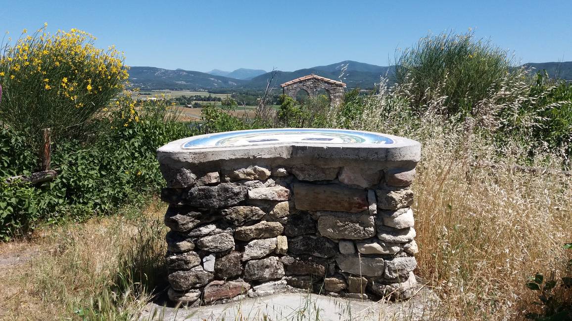 La table d'orientation du Châtelas sur son socle de pierre, la plaine et les collines en arrière-plan