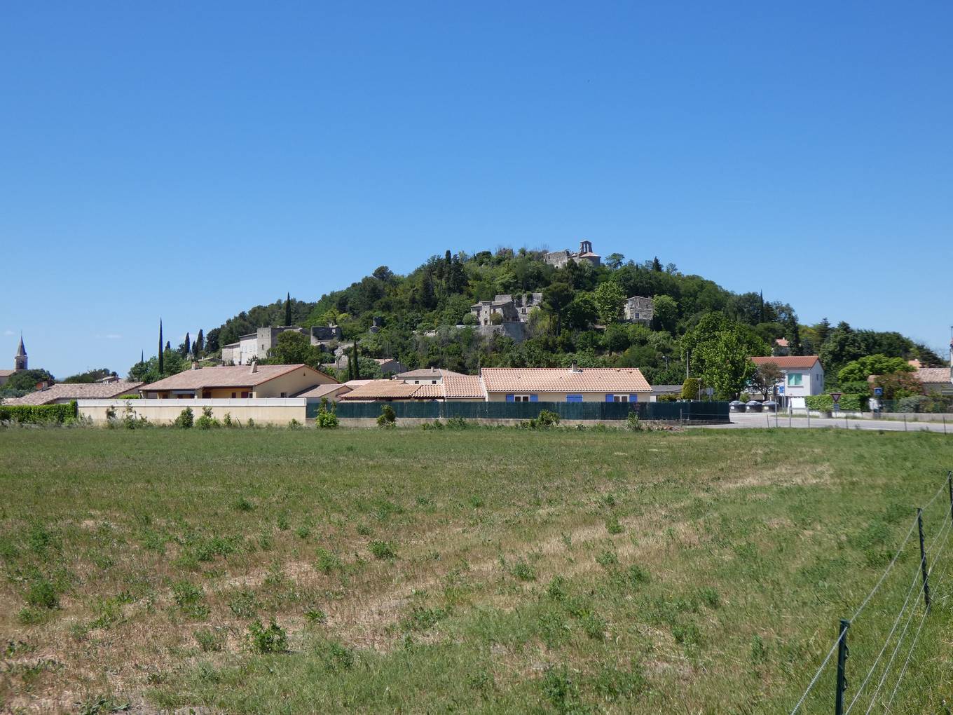 La colline boisée du Châtelas au-dessus des maisons de La Bâtie-Rolland, vue depuis un champ au sud