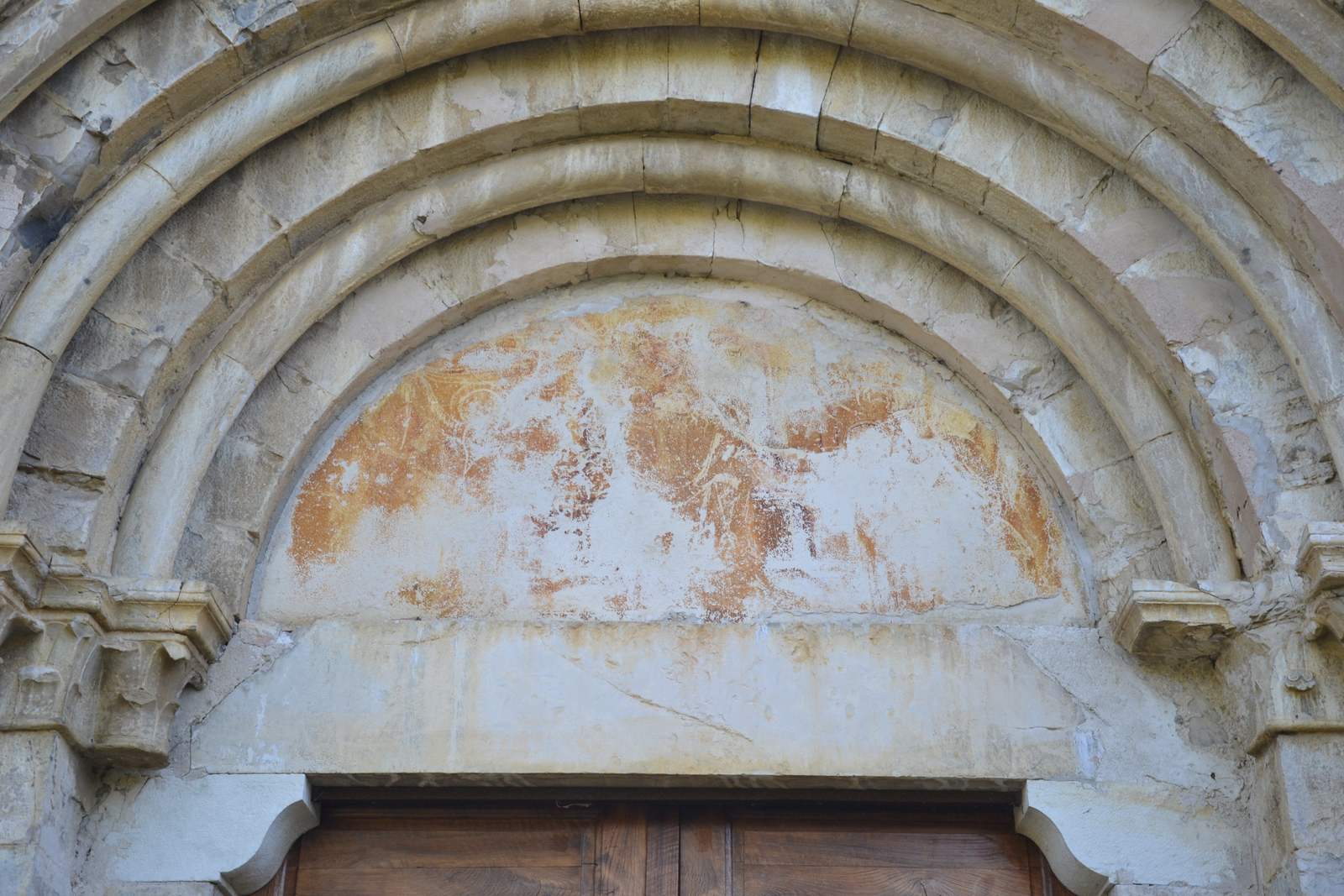 Le tympan du portail de Notre-Dame-de-Calma, trois voussures de pierre claire en plein cintre et, dans le tympan, des restes de peinture ocre et rouge