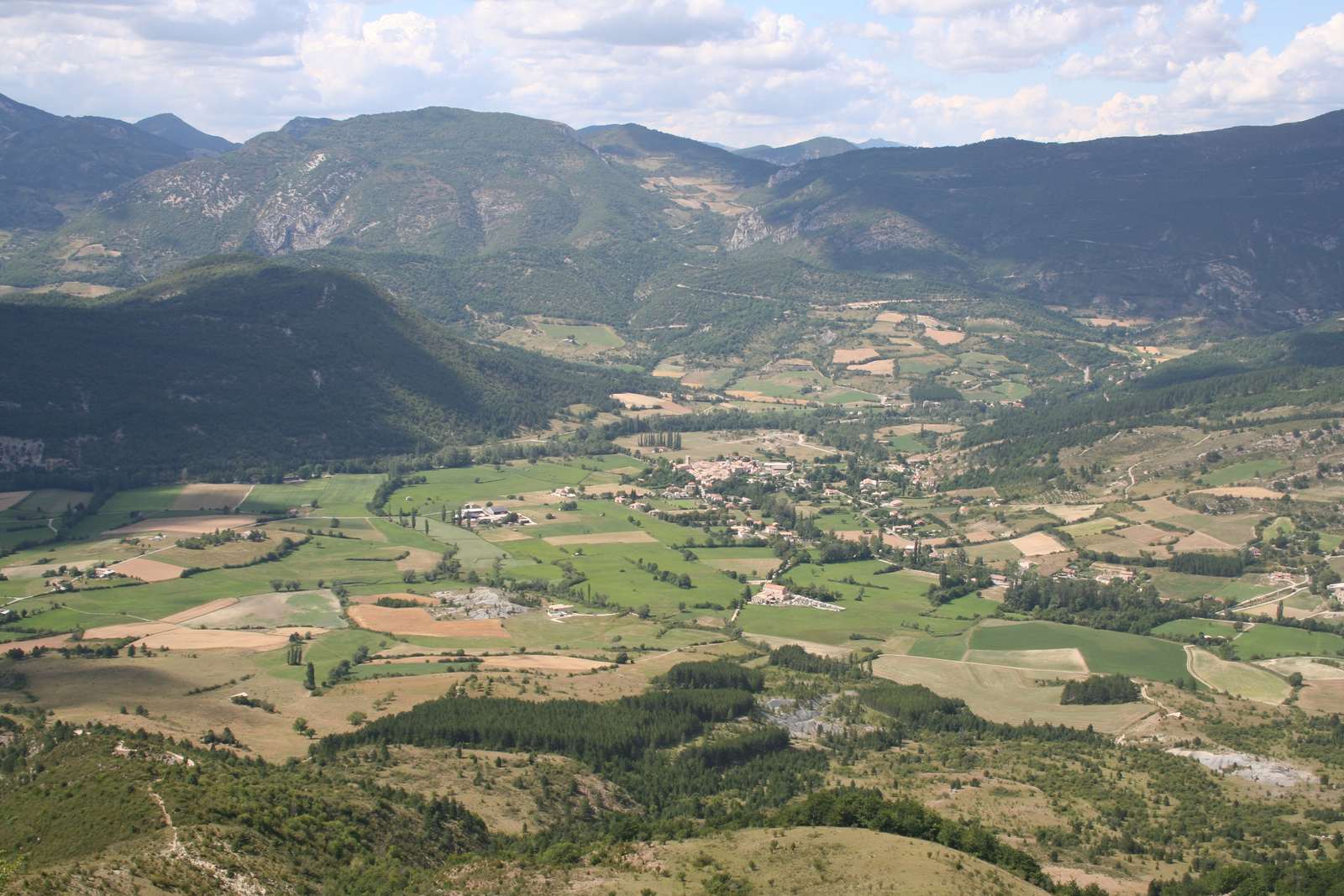 La plaine de Lachau vue d'en haut, une mosaïque de prés verts et de champs autour du village, entourée de montagnes boisées