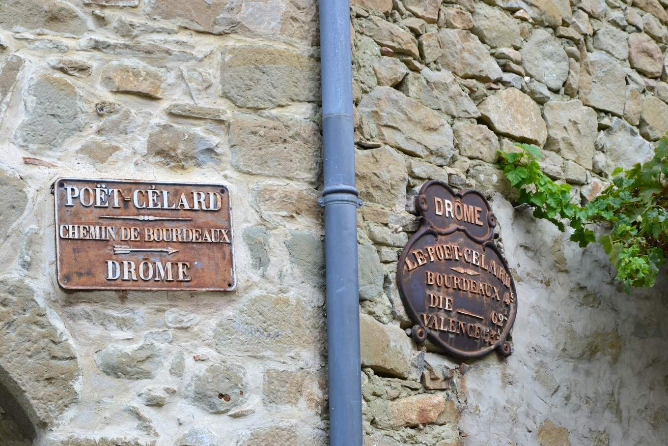 Deux plaques de cocher en fonte sur un mur du Poët-Célard, indiquant Bourdeaux, Die et Valence
