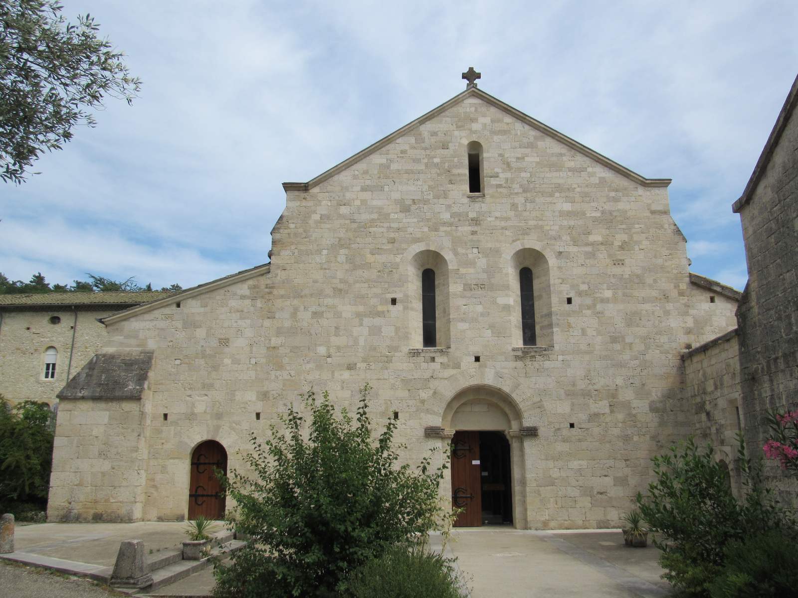 La façade de l'église abbatiale Notre-Dame d'Aiguebelle, pierre nue et ouvertures en plein cintre