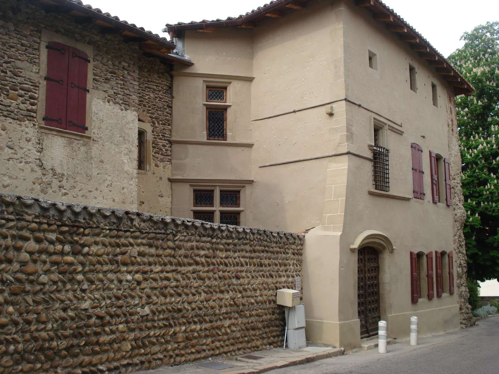 La maison du gouverneur à Moras-en-Valloire, une haute maison claire à fenêtres à meneaux, derrière un mur en galets
