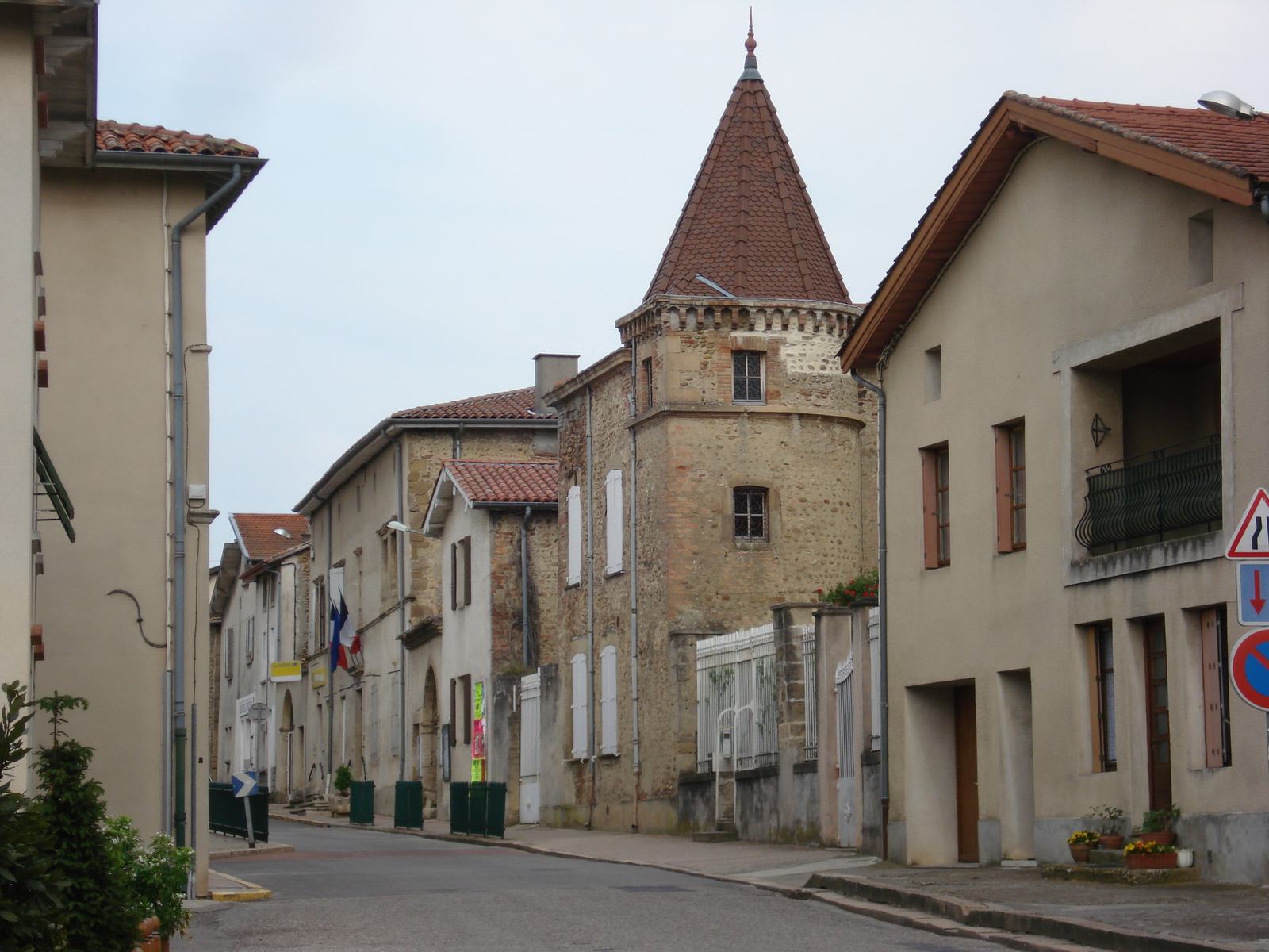 La rue principale de Moras-en-Valloire, maisons claires et une tour carrée coiffée d'un toit pointu