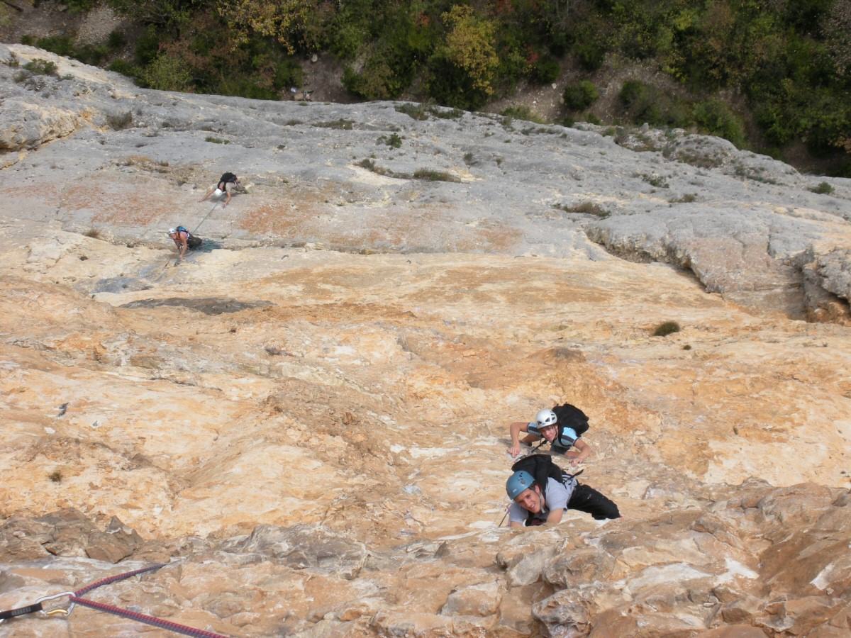 Quatre grimpeurs sur une dalle de calcaire ocre dans les gorges d'Omblèze