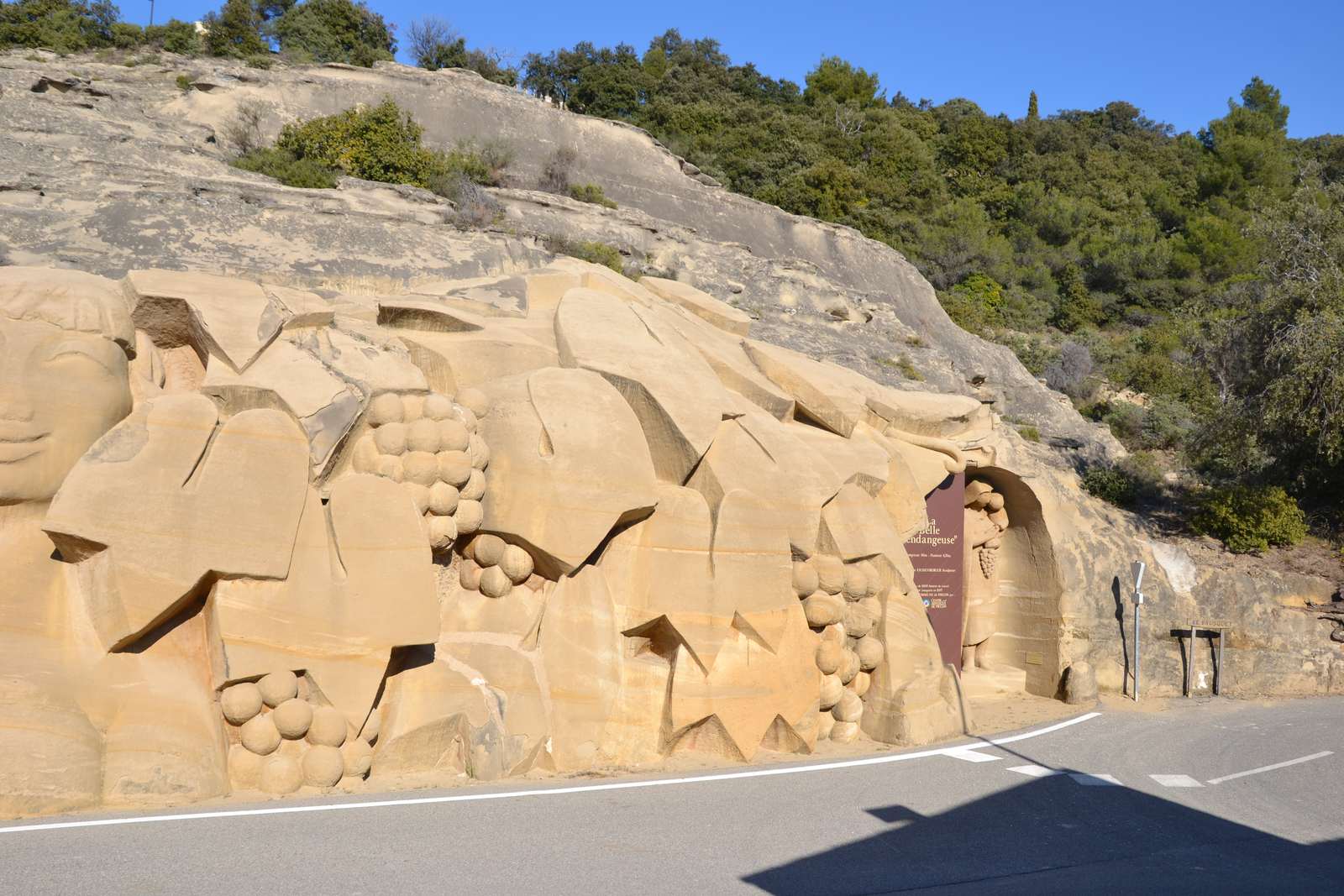 Un rocher de grès au bord de la route, sculpté de grappes de raisin et de feuilles de vigne