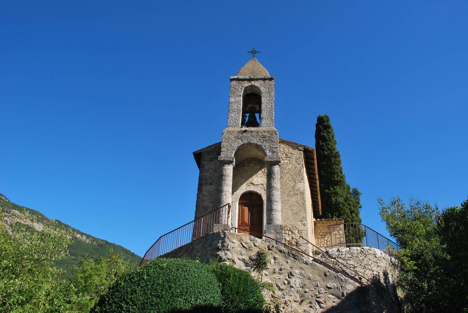 L'église de Saint-Benoit-en-Diois, petite église de pierre avec son clocher, dans un paysage de collines