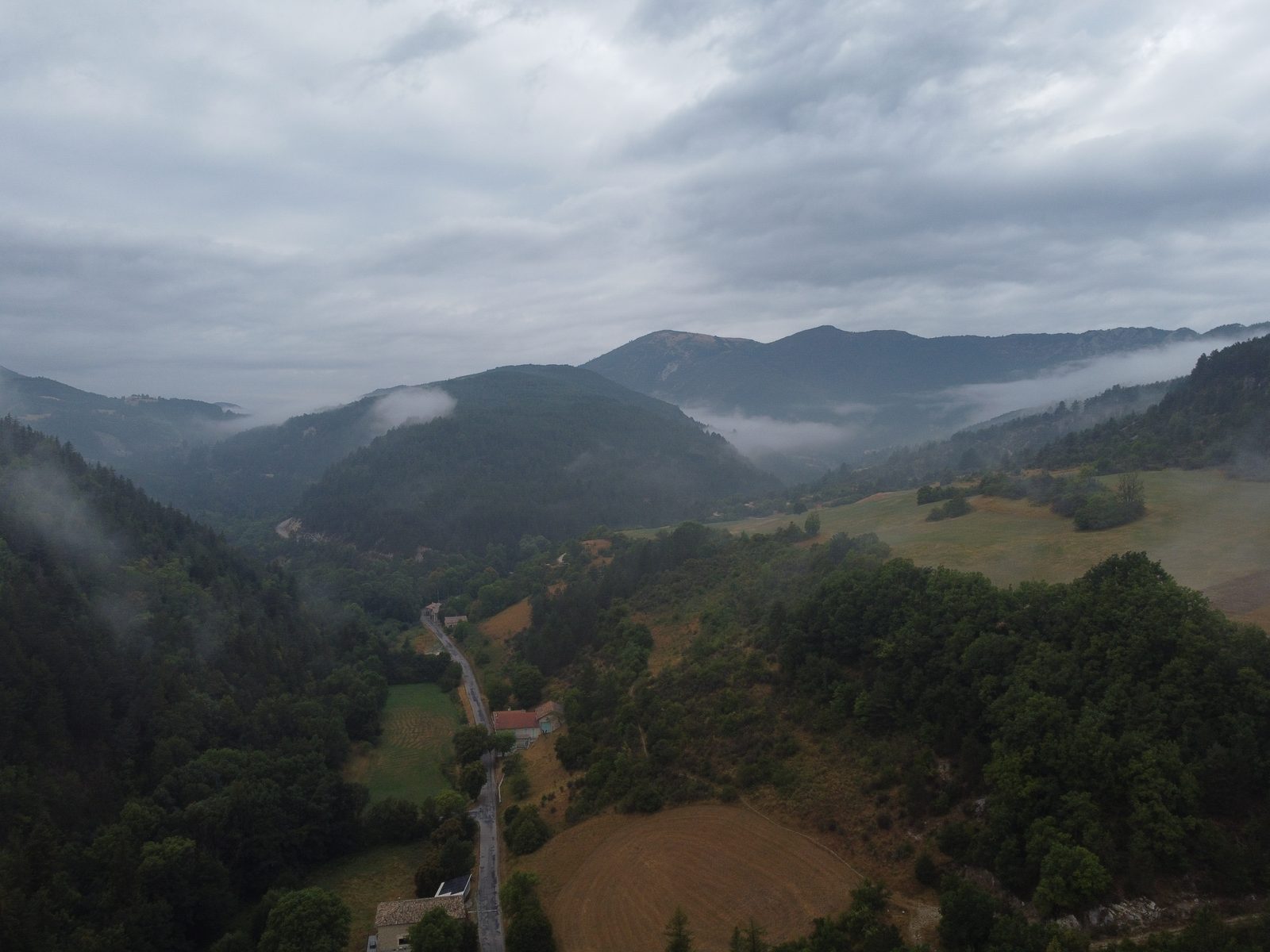 Vallée boisée et crêtes dans les nuages bas autour de Valdrôme