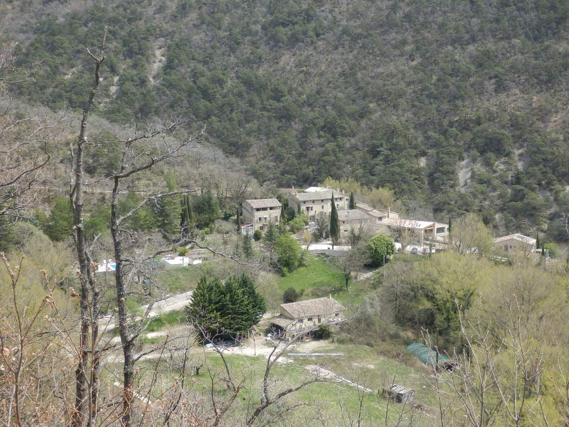 Le hameau des Granges Basses à Valouse, quelques maisons de pierre au pied d'une pente boisée